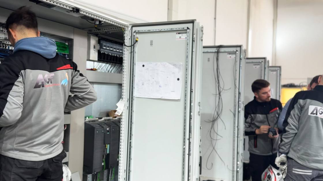 AGF team in front of a row of electrical cabinets in the workshop