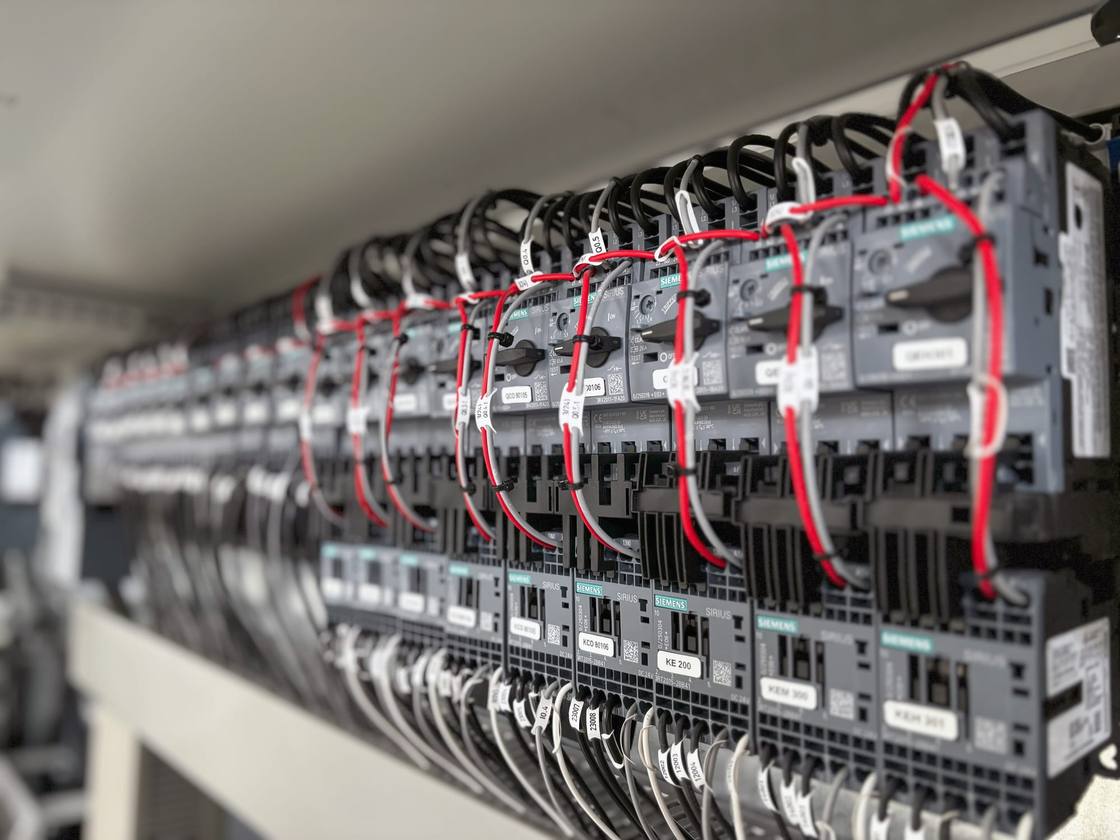 Row of labelled Siemens motor starters and contactors inside a cabinet