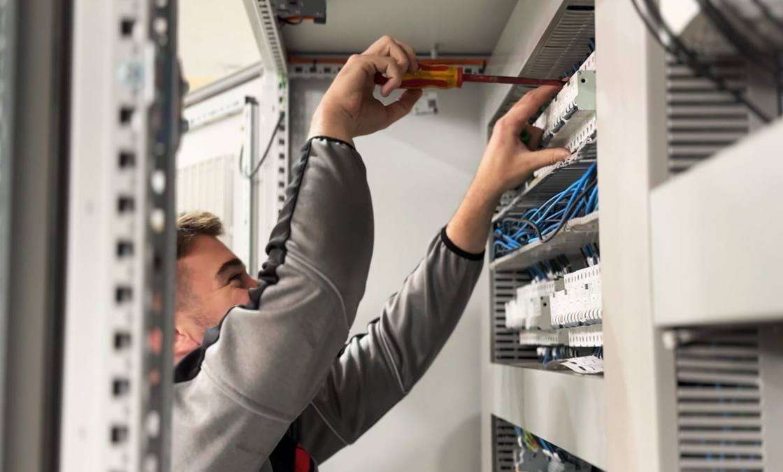 Worker tightening the wiring of an electrical cabinet