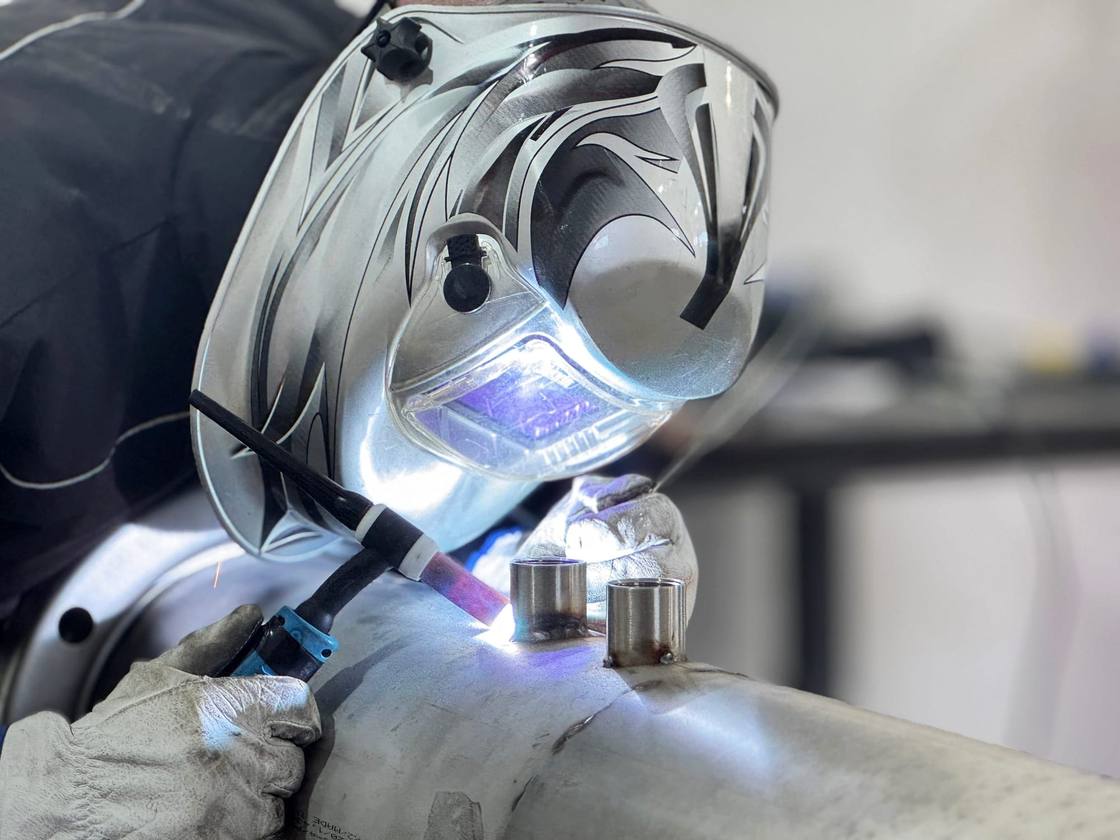 AGF welder in a mask performing TIG welding in the workshop