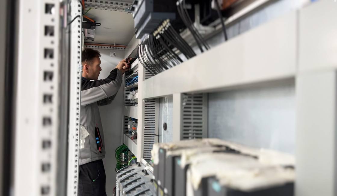 AGF technician working between electrical cabinets under assembly